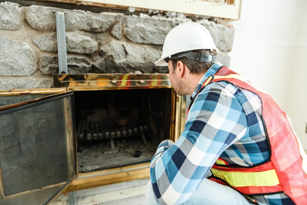 CSIA-certified chimney inspection technician in a hard hat and safety vest looking up at a Portland-area home before beginning an inspection.