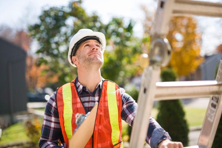 CSIA-certified chimney inspection technician in a hard hat and safety vest looking up at a Portland-area home before beginning an inspection.