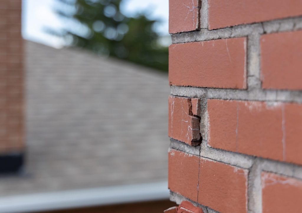Close-up of cracked mortar joints in chimney masonry, a sign a chimney inspection may be needed sooner than scheduled.