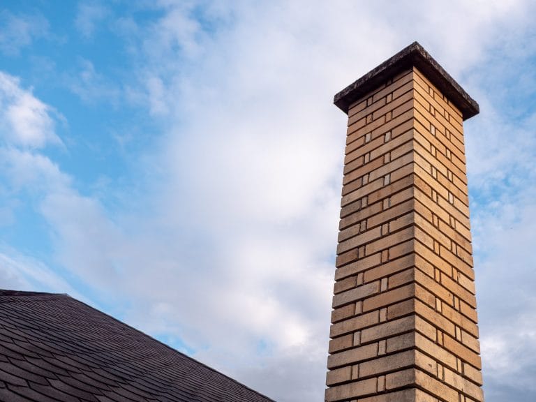 Tan brick chimney with a concrete crown on a Portland-area home.