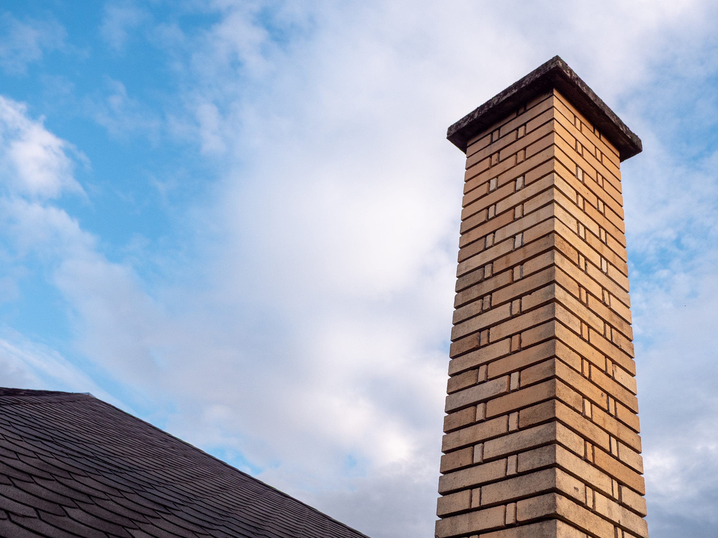 Tan brick chimney with a concrete crown on a Portland-area home.